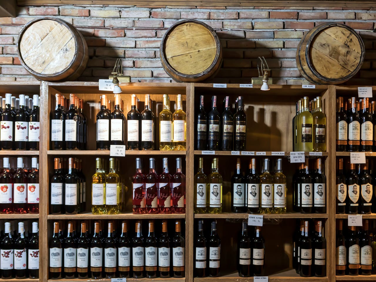 Accueil - Guide Cave à Vin A rustic wine cellar showcasing a variety of wine bottles against a brick wall and wooden barrels.