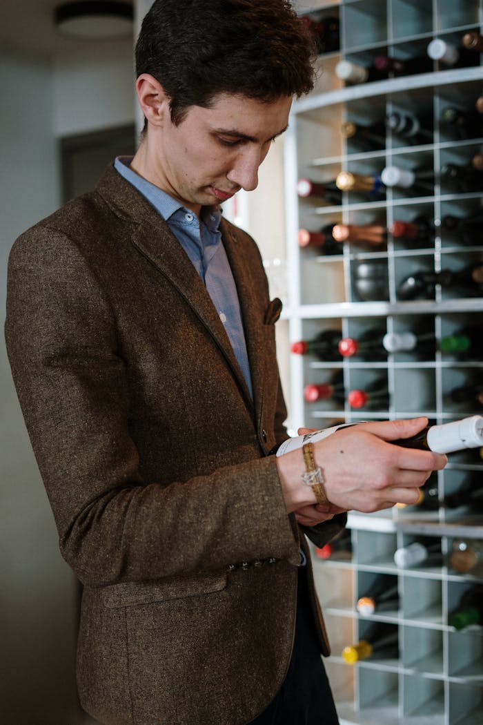 Accueil - Guide Cave à Vin A sommelier examines a wine bottle in a contemporary wine cellar with a diverse wine collection.